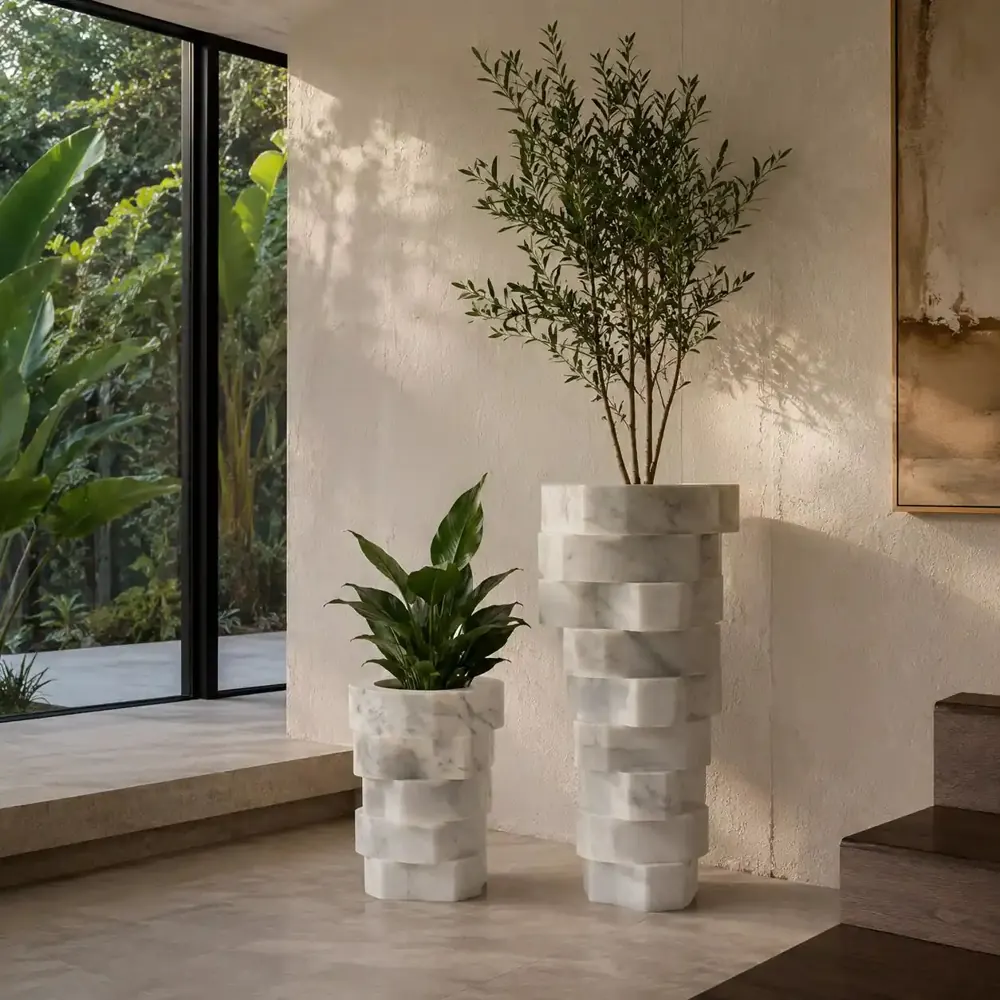 Two faceted white marble planters in different sizes with olive tree and plant