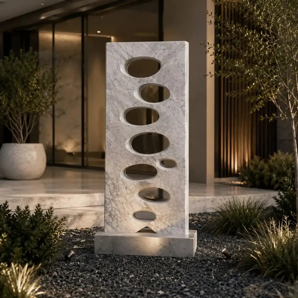 Hand-carved marble screen sculpture with oval cut-outs in a landscaped courtyard, made by Avtikes artisans in Udaipur